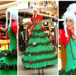 Betoverend kerstentertainment: Kerstboom Lady's Steltenlopers brengen magie met guirlandes en lampjes. Boek nu voor feestelijke sfeer!