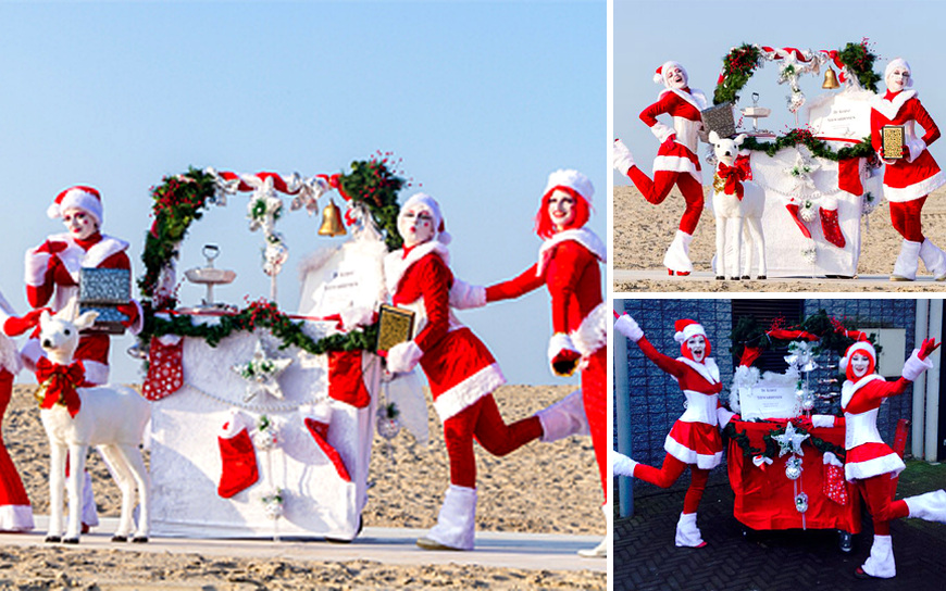 Twee Kerst Stewardessen in rood-witte kerstkostuums met hun feestelijk versierde kerstkar