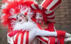 Rood wit steltenlopers duo met bellen tijdens vrolijke steltenlopers act op festival of evenement.