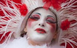 Rood wit steltenlopers duo met bellen tijdens vrolijke steltenlopers act op festival of evenement.