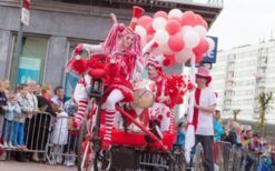 Clown op rood witte driewieler met drumstel tijdens circus thema mobiele act op festival of evenement.