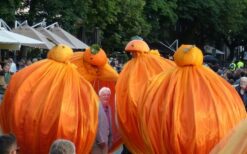 Oranje steltenlopers met grote sinaasappels tijdens een zomers of Koningsdag evenement