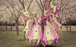 Lente steltenlopers in paars en groen kostuum tijdens kleurrijke steltenlopers act op festival of evenement.