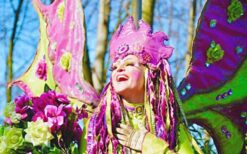 Lente steltenlopers in paars en groen kostuum tijdens kleurrijke steltenlopers act op festival of evenement.