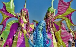 Lente steltenlopers in paars en groen kostuum tijdens kleurrijke steltenlopers act op festival of evenement.