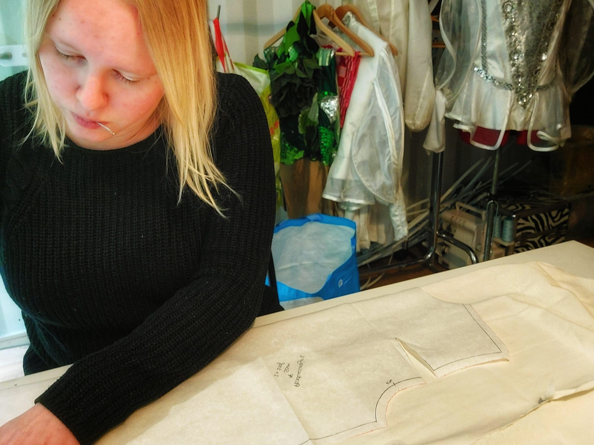 Chantal aan het werk @ Prima Atelier, intens aan het concentreren terwijl ze spelden in haar mond heeft. Dit beeld geeft een glimp van de toewijding en precisie die nodig is om onze kostuums perfect te maken