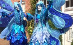 Blauwe winterelfjes steltenlopers tijdens een winterwonderland steltenlopers act op een kerstmarkt of winter evenement.