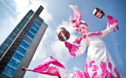 Prinses op stelten in roze wit kostuum met waaiers tijdens een steltenlopers act op een festival of evenement.