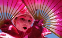 Prinses op stelten in roze wit kostuum met waaiers tijdens een steltenlopers act op een festival of evenement.