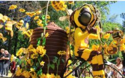 Grote bijen kostuums en dansende bijen tijdens een vrolijke Bijen Parade met duurzame fiets en zwevende bijtjes op een festival of evenement.