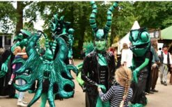 Groene fantasie wezens en steltenlopers tijdens een mysterieuze parade act met natuur en alien thema op een festival of evenement.