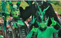 Groene fantasie wezens en steltenlopers tijdens een mysterieuze parade act met natuur en alien thema op een festival of evenement.