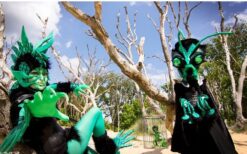 Groene fantasie wezens en steltenlopers tijdens een mysterieuze parade act met natuur en alien thema op een festival of evenement.