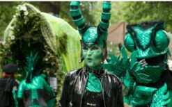 Groene fantasie wezens en steltenlopers tijdens een mysterieuze parade act met natuur en alien thema op een festival of evenement.