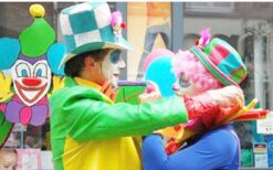 Kleurige clowns schminken kinderen en spelen spelletjes met een karretje vol snoep en ballonnen tijdens vrolijk kinderentertainment op een festival of evenement.