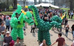 Draken Rijders steltenlopers met grote draken op 5 meter hoogte tijdens mobiel entertainment. Interactieve parade act met muziek en fantasie, ideaal voor festival, evenement en winkelcentrum.