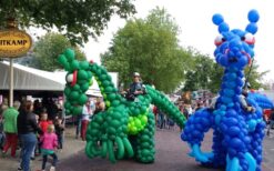 Draken Rijders steltenlopers met grote draken op 5 meter hoogte tijdens mobiel entertainment. Interactieve parade act met muziek en fantasie, ideaal voor festival, evenement en winkelcentrum.