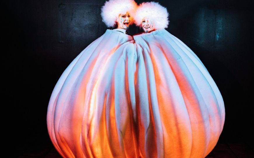 Grote witte sneeuwballen met LED verlichting en performers tijdens een winterse straattheater act