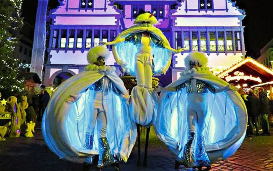 Grote witte sneeuwballen met LED verlichting en performers tijdens een winterse straattheater act