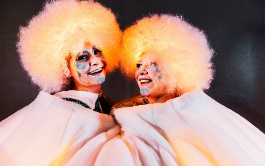 Grote witte sneeuwballen met LED verlichting en performers tijdens een winterse straattheater act