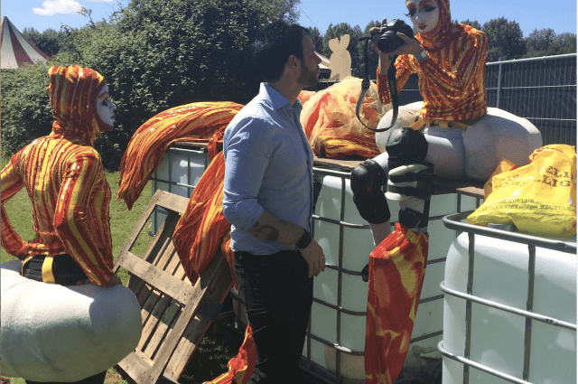 Steltenlopers maken zich gereed om op te treden in Vrolijk & Fleurig, een van onze meest vrolijke zomerse acts op stelten. Buiten op het festival is er voldoende ruimte om heerlijk in het zonnetje de kostuums aan te doen.