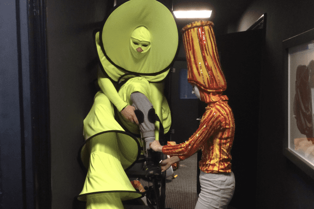 Het is niet altijd mogelijk om het steltenkostuum alleen aan te doen. De Circle Mania in het bijzonder is een van die acts met een uitdaging. Gelukkig was er een collega die kon helpen, waardoor alles op tijd klaar was voor het optreden.